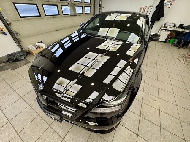 Idealnie wypolerowana maska Mercedesa z odbiciem sufitu oświetleniowego