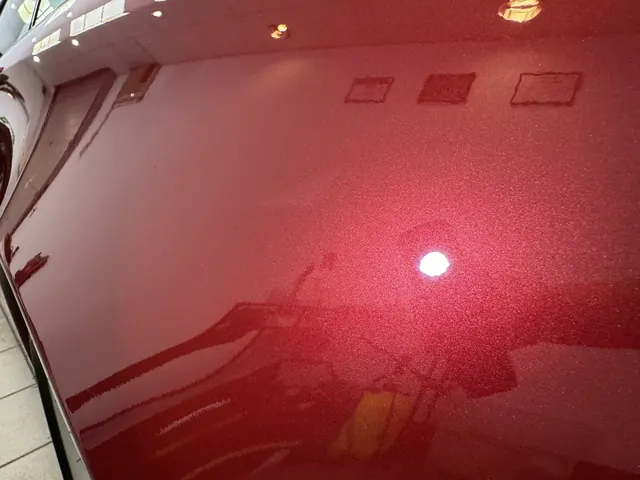 Głęboki bordowy lakier z widocznym metalicznym ziarnem w blasku lampy