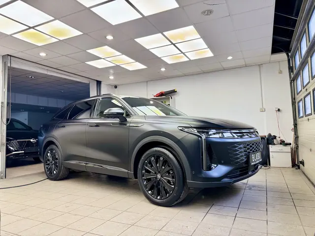 Szary SUV Omoda zaparkowany z przodu w profesjonalnym studio detailingowym